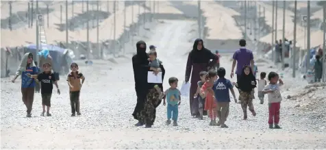  ?? — Reuters ?? Displaced Iraqis, who fled the fighting between the army and the IS, make their way at a refugee camp in Salamiya, Iraq, on Monday.