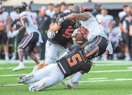  ?? NATHAN J FISH/THE OKLAHOMAN ?? Oklahoma State’s Kendal Daniels (5) and Ben Kopenski (52) tackle Texas Tech’s Tahj Brooks in the third quarter Saturday in Stillwater.