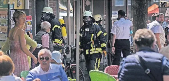  ?? RP-FOTOS (2): MARKUS VAN OFFERN ?? Die Feuerwehr bei ihrem Einsatz an der Dellstraße. Mit Atemschutz ging sie in das Café, draußen wunderten sich die Gäste ein wenig.