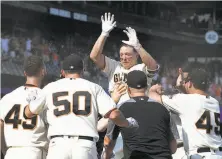  ?? Thearon W. Henderson / Getty Images ?? Nick Hundley leaps into a crowd of teammates after hitting a walk-off home run in the 10th inning to beat the Cardinals.