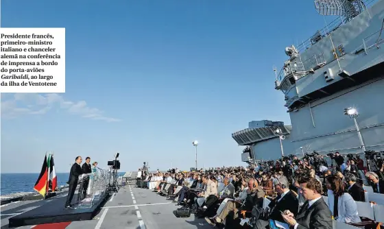  ??  ?? Presidente francês, primeiro-ministro italiano e chanceler alemã na conferênci­a de imprensa a bordo do porta-aviões Garibaldi, ao largo da ilha de Ventotene