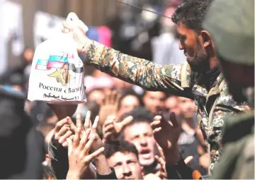  ??  ?? File photo of a Syrian army soldier distributi­ng aid from Russian forces to civilians at a shelter in Adra near Damascus, Syria. —Reuters photo