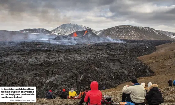  ?? Marco Di Marco/Associated Press ?? > Spectators watch lava flows from an eruption of a volcano on the Reykjanes peninsula in south-west Iceland