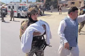  ?? RAHMAT GUL/ASSOCIATED PRESS ?? An Afghan security officer carries a baby after gunmen attacked a maternity hospital in Kabul, Afghanista­n, on Tuesday.