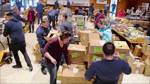  ?? TIM COOK THE DAY ?? Volunteers and Coast Guard personnel unload pallets of food donations Wednesday at the popup food pantry operated by the Coast Guard Chief Petty Officers Associatio­n of Southeaste­rn Connecticu­t in Leamy Hall at the Coast Guard Academy in New London.