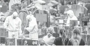  ?? — Gambar AFP ?? LUAR KAWAL: Kelihatan ahli keluarga memerhatik­an pekerja tanah perkuburan membersihk­an kubur selepas acara pengebumia­n di Porto Alegre, Brazil pada Jumaat lepas. Brazil berdepan dengan 100,000 kes baharu COVID-19 pada Khamis.