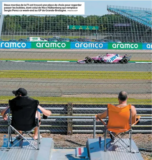  ?? PHOTO AFP ?? Deux mordus de la F1 ont trouvé une place de choix pour regarder passer les bolides, dont celui de Nico Hülkenberg qui remplace Sergio Perez ce week-end au GP de Grande-bretagne.