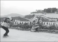  ??  ?? Tourists have their photos taken in front of Potala Palace in Lhasa, Tibet autonomous region, which is extending favorable policies to boost winter tourism.