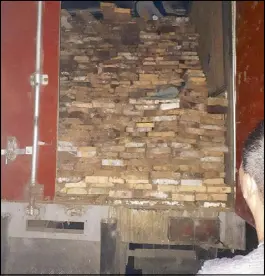  ??  ?? Handout photo shows an officer inspecting the P1.2-million illegal lumber seized in Quezon province recently.