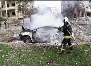  ?? AP ?? This photo released Monday by the Syrian Civil Defense group known as the White Helmets, shows Syrian White Helmet civil defense workers putting out a fire at the site of twin explosions, in the northweste­rn city of Idlib, Syria.
