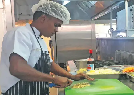  ??  ?? Castaway Island Resort executive sous chef and in charge of the kitchen Denis Chandra prepares vegetables.