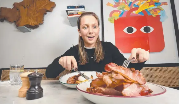  ?? Picture: TONY GOUGH ?? Zoe Kanat tucks into an extra serving of bacon, a popular brunch addition for diners at Victorian cafes.