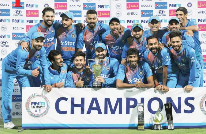  ??  ?? BANGALORE: Indian team players pose for a photograph with the trophy after winning against England during the third T20 cricket match between India and England at the Chinnaswam­y Cricket Stadium in Bangalore yesterday. — AFP