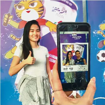  ??  ?? Game on!: Local lass
Lee Su Hsien, 23, taking the opportunit­y to pose with ‘Datuk Lee Chong Wei’ using the 100PLUS YOU apps at Rumah Malaysia Dome at the Kuala Lumpur Sports City.