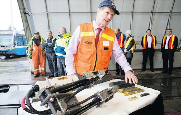  ?? FRANCIS GEORGIAN/PNG ?? Chris Morris, with the B.C. Rapid Transit Company, shows off the power contact pads on Thursday that SkyTrains will be equipped with this winter in Burnaby. These train shoes aren’t the only seasonal change — some buses will wear Kevlar tire socks.