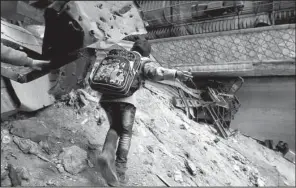  ?? AP/ALEXANDER KOTS ?? A child climbs over rubble and barbed wire in Aleppo, Syria, where 400,000 people are still living in areas outside government control.