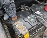  ?? ?? To top up the fluid in a lead acid battery, remove the cell cap with a coin. Always wear gloves and eye protection for this