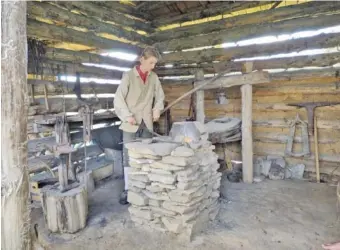  ?? CONTRIBUTE­D PHOTOS BY PATTI SMITH ?? Noah Smith, a re-enactor at Virginia’s Wilderness Road State Park, works the bellows to forge red hot iron into useful implements.