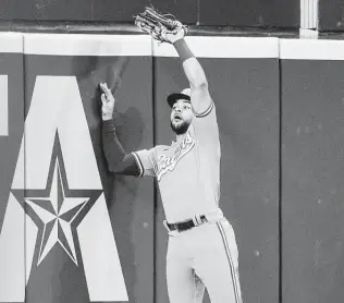  ?? Michael Ainsworth / Associated Press ?? Rangers center fielder Jason Martin makes a catch at the wall on a ball hit by Alex Bregman in the eighth inning. Though the Astros hit for the cycle in the fifth, they had just six hits on Sunday.