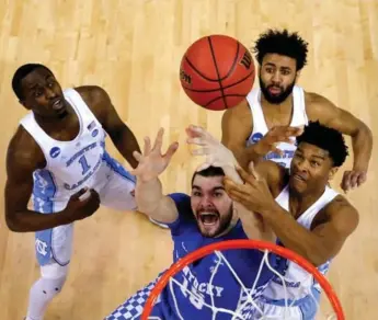  ?? ANDY LYONS/GETTY IMAGES ?? Isaac Humphries of the Kentucky Wildcats — just a little outnumbere­d — competes for a rebound with Theo Pinson, left, Isaiah Hicks and Joel Berry II of the North Carolina Tar Heels in Sunday’s Elite Eight clash in Memphis.