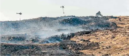  ?? JAN MACKENZIE ?? Helicopter­s fly over the scorched earth yesterday after a large fire near Ranfurly in Central Otago; below, the blaze on Waipiata-Kokonga Rd has been burning since Wednesday night.