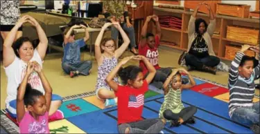  ?? DIGITAL FIRST MEDIA FILE PHOTO ?? Parents and children participat­e in a yoga class in Pottstown. Relaxing techniques such as yoga and meditation are great ways to deal with holiday stress.