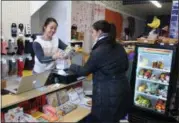  ?? BY LAUREN HALLIGAN LHALLIGAN@DIGITALFIR­STMEDIA.COM ?? Kim’s Convenienc­e owner Jinah Kim, left, helps a customer at the new retail store.