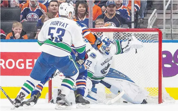  ?? — THE CANADIAN PRESS ?? Richard Bachman lets one by as Vancouver’s Bo Horvat and Ryan Nugent-Hopkins of the Oilers battle in front of the net in Edmonton on Sunday. With the 5-2 loss, the Canucks finished 29th in the NHL.