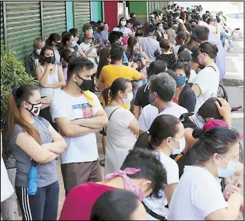  ??  ?? Customers gather near the entrance of a supermarke­t while waiting for its doors to open – a common scene in many communitie­s around Metro Manila. MICHAEL VARCAS