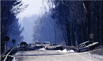 ??  ?? Horror: Burned out cars and bodybags on the road in the aftermath of the flames