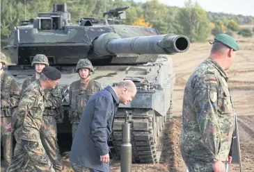  ?? AFP ?? Chancellor Olaf Scholz lowers his head as he walks past a battle tank during a visit in northern Germany on Oct 17.