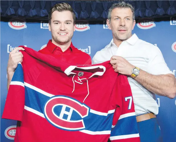 ?? — THE CANADIAN PRESS ?? Newly acquired Montreal Canadien Jonathan Drouin, left, gets his jersey from general manager Marc Bergevin as he is introduced to the media during a press conference at the Bell Centre in Montreal on Thursday.