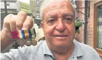  ??  ?? Ken Davies with mini replicas of medals, including the VC awarded to his grandfathe­r James Llewellyn Davies