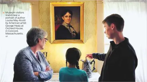  ?? AP ?? Museum visitors stand near a portrait of author Louisa May Alcott by American artist George Healy at Orchard House, in Concord, Massachuse­tts.