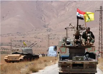  ?? (Reuters) ?? HEZBOLLAH AND Syrian flags flutter on a military vehicle in Western Qalamoun, Syria in August.