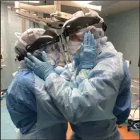 ?? The Associated Press ?? HOPE AND LOVE: In this March 30 photo provided by Chief Nurse Anesthetis­t Nicole Hubbard, nurses Mindy Brock and Ben Cayer, wearing protective equipment, hold each other and look into each other’s eyes in Tampa General Hospital in Tampa, Fla.
