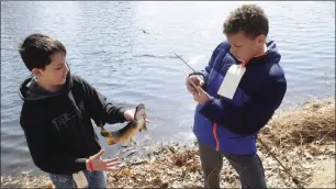  ?? Photo by Ernest A. Brown ?? Scott Fernandes, 11, left, tries to hold his trout steady while his friend Jadis Williams, also 11, takes a picture of it during the annual Ernest Carignan Fishing Derby at Cass Pond in 2018.