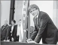  ?? AP/MANU FERNANDEZ ?? Carles Puigdemont, the regional president of Catalonia, signs an independen­ce declaratio­n document after a parliament­ary session Tuesday in Barcelona.