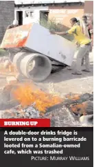  ?? PICTURE: MURRAY WILLIAMS ?? BURNING UP A double-door drinks fridge is levered on to a burning barricade looted from a Somalian-owned cafe, which was trashed