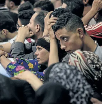  ?? MOHAMED EL-SHAHED/GETTY IMAGES ?? Relatives of killed Coptic Christians grieve by the coffins during the funeral at Abu Garnous Cathedral in the north Minya town of Maghagha, on Friday. Egypt launched an air strike on a jihadist training camp after masked gunmen attacked a bus of...