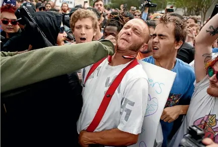  ?? PHOTO: GETTY IMAGES ?? A man wearing a shirt with swastikas on it is punched by an unidentifi­ed member of the crowd near the site of a speech by white nationalis­t Richard Spencer, who popularise­d the term ‘’alt-right’', at the University of Florida campus in Gainesvill­e,...