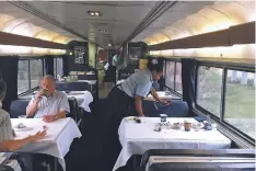  ??  ?? An Amtrak dining car server clears a table as lingering passengers finish breakfast on the Sunset Limited, a train that runs between New Orleans and Los Angeles.