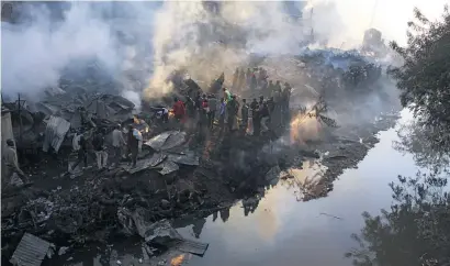  ?? Picture: AFP ?? LIVES IN RUINS. Debris smoulders after a fire gutted a timber dealership at Gikomba market and spread to nearby stalls and homes in Nairobi yesterday. Nine of the dead were in flats next to the market.