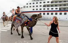  ?? — EPA ?? Riding high: Tourists riding camels near the cruise ship docked at La Goulette port of Tunis in Tunisia.