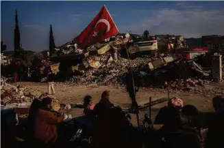  ?? Bernat Armangue/Associated Press ?? A family sits next to a collapsed building as they wait for the bodies of their relatives to be recovered from under the rubble in Antakya, Turkey, on Saturday. Rescue teams using thermal cameras to locate signs of life are continuing to pull survivors out of mounds of rubble, five days after a major earthquake struck a sprawling border region of Turkey and Syria.