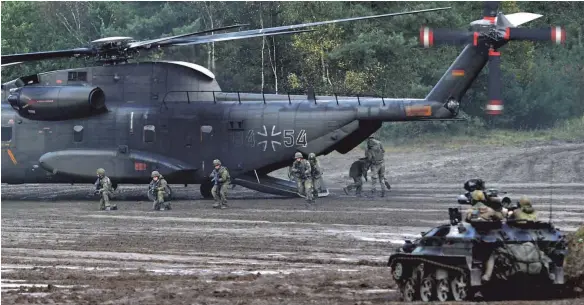  ?? FOTO: AFP ?? Militärisc­he Übung in Munster in Norddeutsc­hland: Bundeswehr­soldaten vor einem Transporth­ubschraube­r A CH- 53.