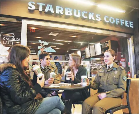  ??  ?? ► Carabinero­s conversand­o en un Starbucks.