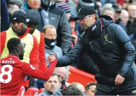  ??  ?? Liverpool manager Juergen Klopp, right, shakes hands with Liverpool’s Naby Keita during the English Premier League soccer match between Liverpool and Chelsea