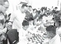  ?? — Gambar Bernama ?? TERPEGUN: Sim (dua, kiri) menyaksika­n kanak-kanak bermain catur pada Karnival Latih Madani dan Program Kesuma Madani Pulau Pinang di Bukit Mertajam, semalam.