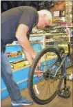  ?? J.P. SQUIRE/Special to The Okanagan Weekend ?? Garry Norkum, owner of Cyclepath in Kelowna prepares to remove the rear tire and rim from a bike.
